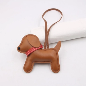 Brown leather puppy bag charm with white stitching and decorative red collar on a strap