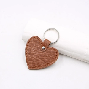 Detail of the brown textured leather heart-shaped keychain with silver metal ring