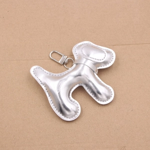 Détail d'un pendentif chien en cuir argenté avec surpiqûres et fermoir homard