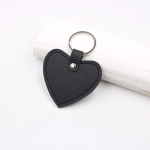 Detail of a black leather heart keychain with textured finish and silver metal ring