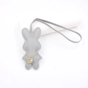 Nahaufnahme von grauem Kaninchen-Lederanhänger mit Goldkette und feiner Nahtverzierung