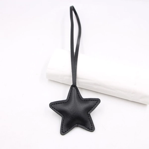 Minimalist black leather star bag charm with litchi texture and long strap detail