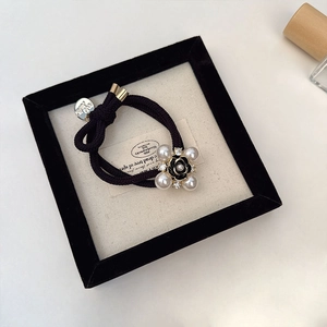 Close-up of camellia hair tie with pearls and gold buckle in a display box