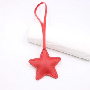 Close-up of red leather star-shaped bag charm with fine stitching and slim lanyard