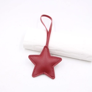 Detail of red leather star-shaped bag charm with lychee texture and stitching