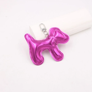 Détail du pendentif chiot en cuir rose métallisé avec fermoir argenté et couture blanche