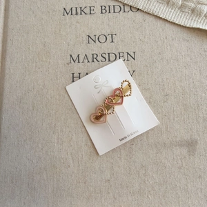 Detail of three pink heart hair clips with gold bead borders on a product card