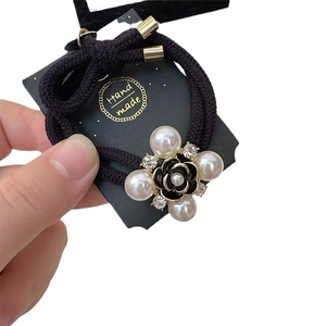 Elegant black camellia hair tie with large faux pearls and crystals on a handmade card