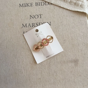 Detail of gold-tone heart hair clip with pink enamel inlay on display card