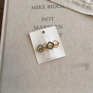 Detail of a gold geometric hair clip with blue enamel circles on a rustic linen background