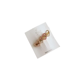 Elegant gold heart hair clip with pink enamel details mounted on white card packaging
