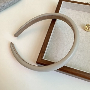 Detail of cream-colored faux leather headband with non-slip velvet lining on wooden frame