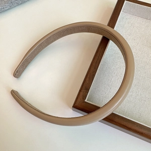 Detail shot of a tan faux leather headband with anti-slip velvet lining and fine stitching
