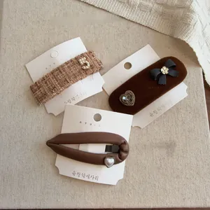 Close-up of three brown hair clips featuring tweed, velvet bows, and pearl heart details