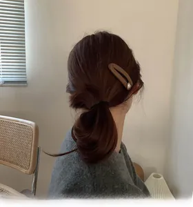 Detail of caramel oval hair clip with white pearl accent worn on model hair