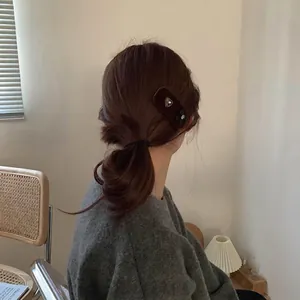 French brown velvet hair clip with a metal heart and black bow on a model