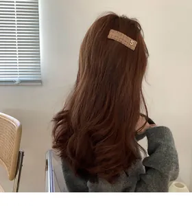 Close-up of brown tweed rectangular hair clip with golden number 5 on wavy hair