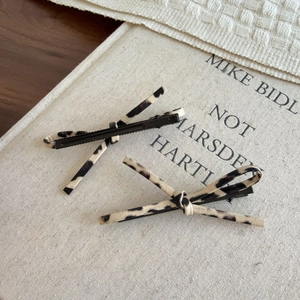 Detail view of leopard print bow hair clips with metal duckbill clips on a book cover