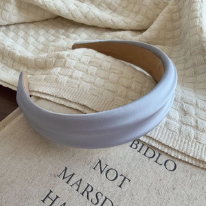 Detail of light blue satin padded headband on a textured fabric background