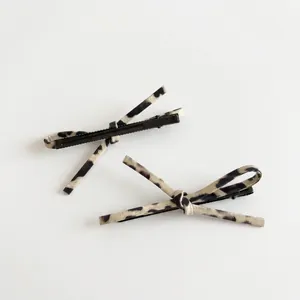Pair of leopard print bow hair clips with black metal alligator grip on white backdrop