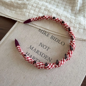 Detail of red and white plaid headband with teeth on a book and waffle blanket