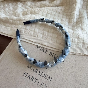 Detail of blue plaid fabric headband with non-slip teeth resting on a book