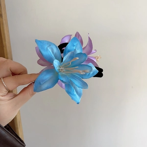 Detail showing the realistic lily flower hair claw clip in blue and purple gradient fabric
