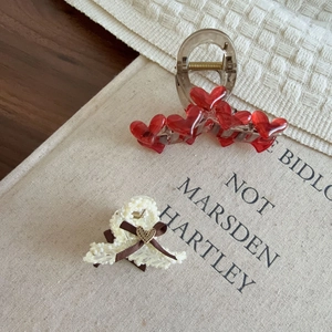 Detailed view of red heart hair claw clip and elegant white pearl bow shark clip