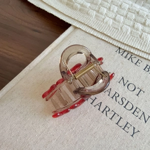 Brown resin heart hair claw clip with red wave patterns on a vintage book background