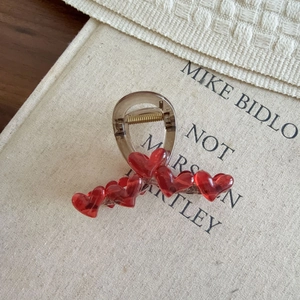 Detailed view of brown resin hair claw with 3D red heart accents on vintage book