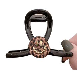 Elegant black resin hair claw clip with leopard print and golden smiley face detail