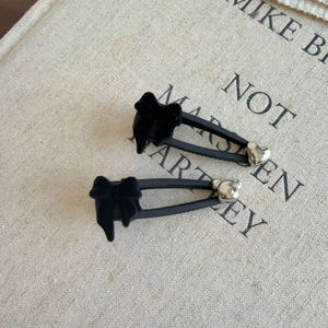 Détail de barrettes noires floquées avec breloques cœur et ours en métal argenté