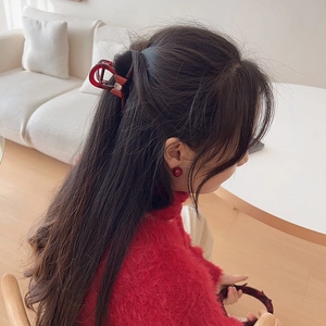 Elegant deep red bow hair claw and matching earrings worn by a model in a cozy sweater