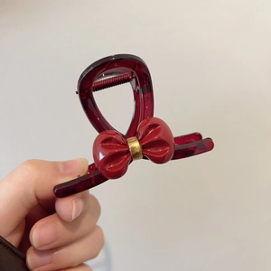 Detailed view of a burgundy resin hair claw clip with a stylish 3D bow and gold ring