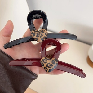 Détail de deux grandes pinces à cheveux noir et bordeaux avec motif cœur léopard chic