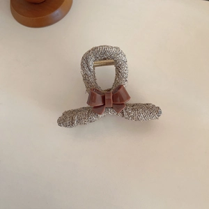 Detail of tweed fabric hair claw with a glossy brown resin bow for autumn hairstyle