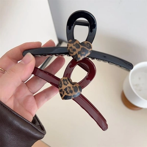 Détail de grandes pinces à cheveux avec cœur léopard en noir et marron et ressort en métal