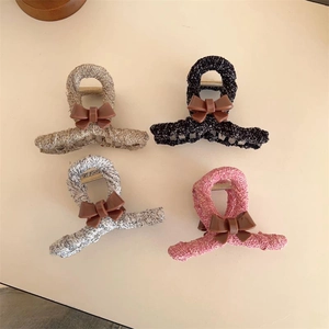 Close-up of four tweed-covered hair claws with resin bows in black, pink, and white