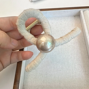 Close-up of beige woven knit hair claw clip featuring a large metallic bead detail