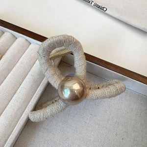 Elegant woven knit hair claw clip with large faux pearl accent on beige velvet base