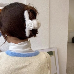 Pince à cheveux camélia en peluche d'hiver présentée sur les cheveux d'un mannequin blanc