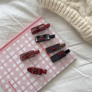 Detail of 6pcs plaid hair clips with resin cherries and embroidered bows on soft fabric