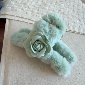 Détail de la pince à cheveux en peluche vert menthe avec fourrure et fleur de camélia