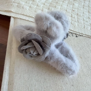 Vue détaillée d'une pince à cheveux en peluche grise avec une fleur de camélia en tissu