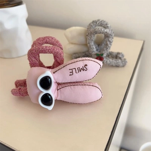 Détail d'une pince à cheveux en peluche rose avec oreilles de lapin et mini lunettes