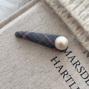 Detail einer grau-violett karierten Haarspange mit einer großen weißen Perlenverzierung