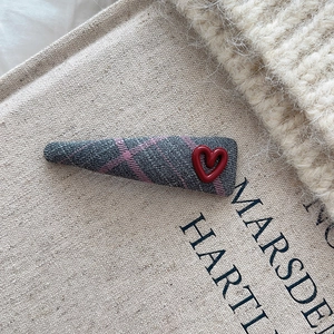 Detailansicht einer Vintage-Haarklammer mit Karomuster und glänzendem rotem Herz-Dekor