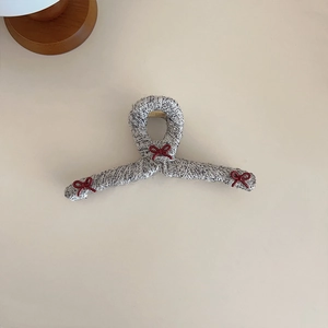 Detail of tweed hair claw clip featuring grey woven fabric and small dark red bows