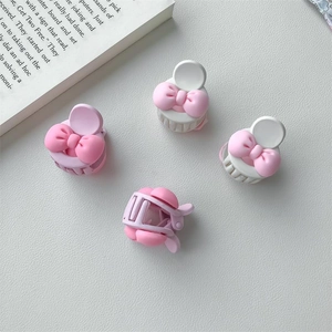 Détail de quatre mini pinces à cheveux à nœuds roses en couleurs crème et pastel