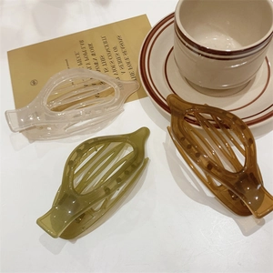 Dettaglio di fermagli per capelli geometrici cavi in bianco, verde e marrone ambra